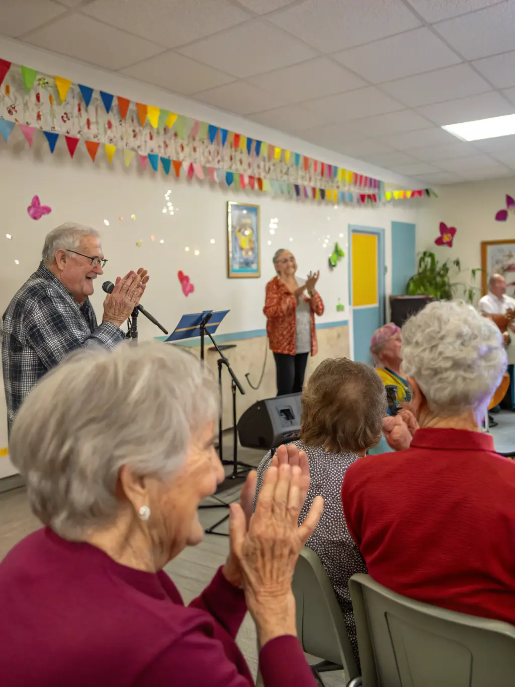 An image capturing a group of seniors enjoying a traditional music performance at a senior center, emphasizing the organization's efforts to cater to all age groups.